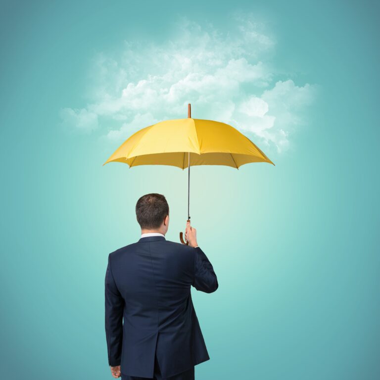 Young business man in blue suit holding yellow umbrella